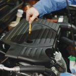 Technician checking engine oil level with dipstick — industrial lubrication maintenance solution for heavy machinery and automotive engines.