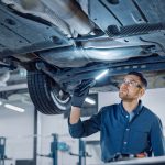 A mechanic inspecting a vehicle for its maintenance and service requirements.
