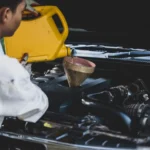 Mechanic pouring fresh engine oil into truck engine at auto repair shop