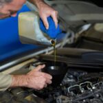 Mechanic pouring oil into car engine by professional oil specialists