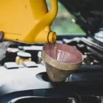 Auto mechanic hand pouring fresh diesel engine oils during vehicle maintenance