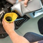 Pouring transmission fluid into vehicle engine using funnel for maintenance and smooth performance