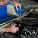 A mechanic at LSA Oils pouring the motor oil into a vehicle engine at High Wycombe in WA