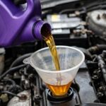 Golden automotive lubricants pouring from a purple jug into engine